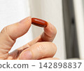 Brown gel pills, dark red capsules close up 142898837