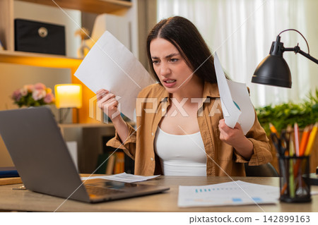 Young woman on home table frustrated by work reports finding mistakes and tossing papers in stress Young woman on home table frustrated by work reports finding mistakes and tossing papers in stress 142899163