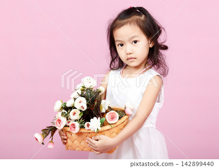 Little girl in white dress holding a basket of flowers, romantic and sweet childhood portrait, spring fashion. Little girl in white dress holding a basket of flowers, romantic and sweet childhood portrait, spring fashion. 142899440