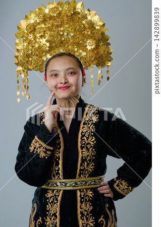 Young Indonesian Asian Woman Wearing Ornate Gold Headdress And Embroidered Traditional Costume, Studio Portrait Young Indonesian Asian Woman Wearing Ornate Gold Headdress And Embroidered Traditional Costume, Studio Portrait 142899839