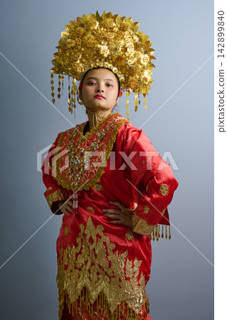 Portrait Of Indonesian Asian Woman In Red Traditional Costume With Ornate Gold Headdress And Embroidery Portrait Of Indonesian Asian Woman In Red Traditional Costume With Ornate Gold Headdress And Embroidery 142899840
