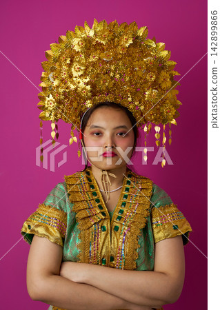 Portrait Of Young Indonesian Asian Woman Wearing Ornate Gold Traditional Headdress And Cultural Costume Portrait Of Young Indonesian Asian Woman Wearing Ornate Gold Traditional Headdress And Cultural Costume 142899866