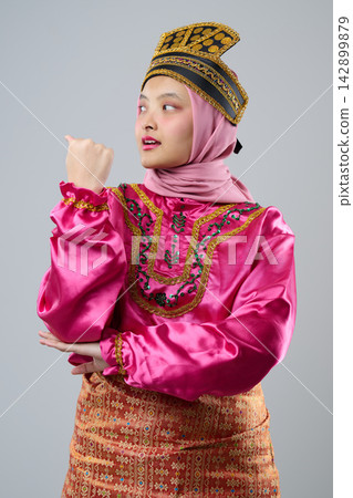Young Indonesian Asian Woman In Pink Traditional Malay Costume And Hijab Wearing Ornate Headpiece Celebrating Cultural Heritage 142899879