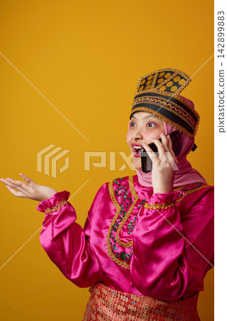 Indonesian Asian Woman in Pink Traditional Costume and Hijab Talking on Phone With Surprised Expression Indonesian Asian Woman in Pink Traditional Costume and Hijab Talking on Phone With Surprised Expression 142899883