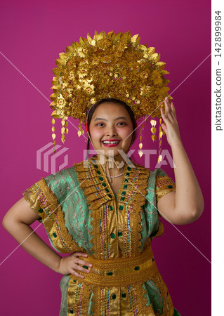 Smiling Indonesian Asian Woman Wearing Ornate Gold Headdress And Traditional Embroidered Costume For Cultural Festival Smiling Indonesian Asian Woman Wearing Ornate Gold Headdress And Traditional Embroidered Costume For Cultural Festival 142899984