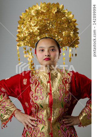 Young Indonesian Asian Woman Wearing Ornate Gold Headdress and Red Embroidered Traditional Costume Young Indonesian Asian Woman Wearing Ornate Gold Headdress and Red Embroidered Traditional Costume 142899994