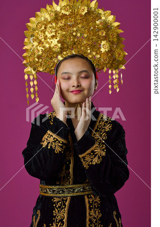 Young Indonesian Asian Woman Wearing Elaborate Gold Headdress and Embroidered Traditional Costume, Eyes Closed, Portrait Young Indonesian Asian Woman Wearing Elaborate Gold Headdress and Embroidered Traditional Costume, Eyes Closed, Portrait 142900001