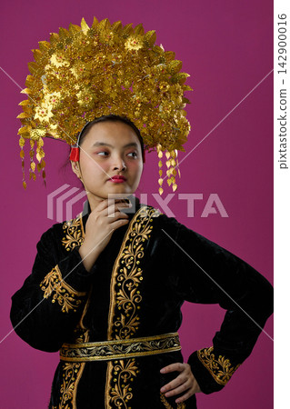Young Indonesian Asian Woman Wearing Ornate Golden Headdress And Embroidered Traditional Velvet Costume Young Indonesian Asian Woman Wearing Ornate Golden Headdress And Embroidered Traditional Velvet Costume 142900016