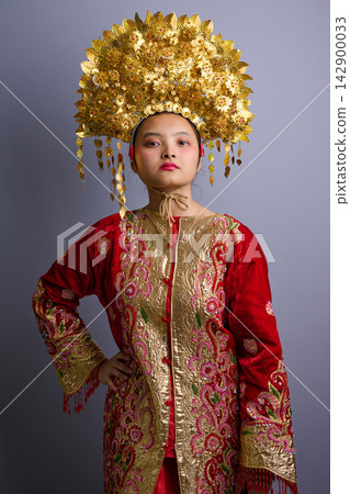 Young Indonesian Asian Woman Wearing Ornate Gold Headdress And Embroidered Red Traditional Costume Portrait Young Indonesian Asian Woman Wearing Ornate Gold Headdress And Embroidered Red Traditional Costume Portrait 142900033
