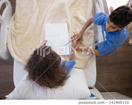 Children drawing together in a Middle Eastern hospital bed while receiving pediatric care and support Children drawing together in a Middle Eastern hospital bed while receiving pediatric care and support 142900118