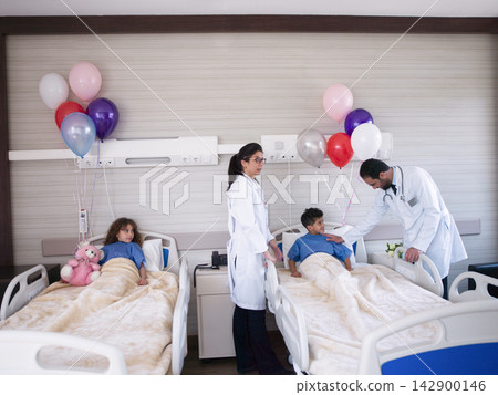 Middle Eastern doctors comforting pediatric patients in a hospital room with balloons and teddy bear 142900146