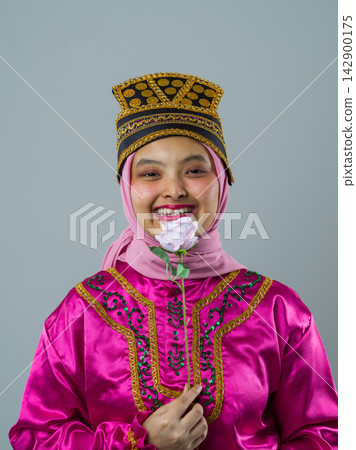 Smiling Young Muslim Indonesian Asian Woman In Pink Traditional Costume And Hijab Holding A Rose Smiling Young Muslim Indonesian Asian Woman In Pink Traditional Costume And Hijab Holding A Rose 142900175