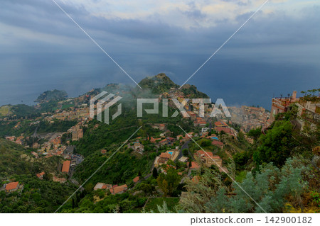 Aerial view of a coastal town nestled on green hills overlooking the deep blue Mediterranean sea Aerial view of a coastal town nestled on green hills overlooking the deep blue Mediterranean sea 142900182