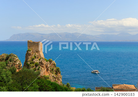 Ancient stone watchtower standing on a rugged cliff overlooking the blue Mediterranean sea Ancient stone watchtower standing on a rugged cliff overlooking the blue Mediterranean sea 142900183
