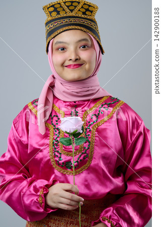 Smiling Young Indonesian Asian Girl Wearing Pink Hijab and Traditional Costume Holding a Rose Portrait Smiling Young Indonesian Asian Girl Wearing Pink Hijab and Traditional Costume Holding a Rose Portrait 142900188