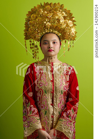 Young Indonesian Asian Girl Wearing Traditional Chinese Golden Headdress and Embroidered Red Ceremonial Costume Young Indonesian Asian Girl Wearing Traditional Chinese Golden Headdress and Embroidered Red Ceremonial Costume 142900214
