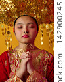 Young Indonesian Asian Girl Wearing Traditional Chinese Gold Headdress and Red Ceremonial Dress With Eyes Closed 142900245