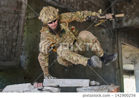Tactical Soldier in Camouflage Gear Jumping Over Rubble During Urban Combat Training Exercise Tactical Soldier in Camouflage Gear Jumping Over Rubble During Urban Combat Training Exercise 142900256