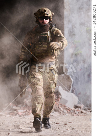 Bearded Soldier in Tactical Gear Walking Through Dusty Urban Ruins With Rifle and Body Armor Bearded Soldier in Tactical Gear Walking Through Dusty Urban Ruins With Rifle and Body Armor 142900271