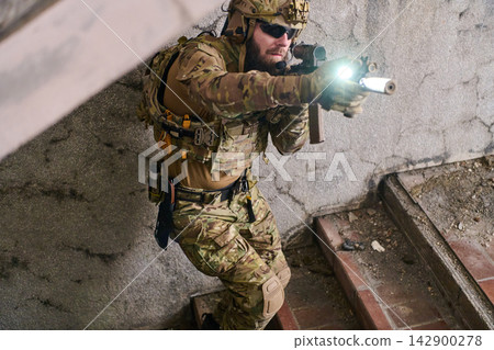 Tactical Soldier in Camouflage Gear Aiming Rifle With Weapon Light in Urban Stairwell Tactical Soldier in Camouflage Gear Aiming Rifle With Weapon Light in Urban Stairwell 142900278