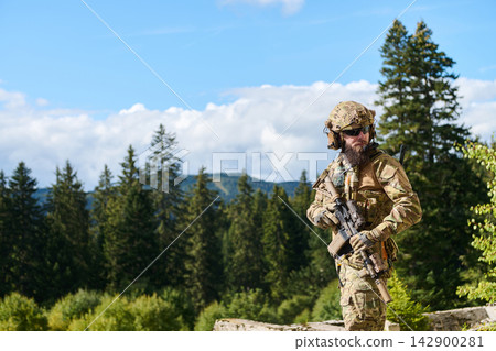 Armed Special Forces Soldier in Multicam Camouflage Standing in Forest Mountain Landscape 142900281