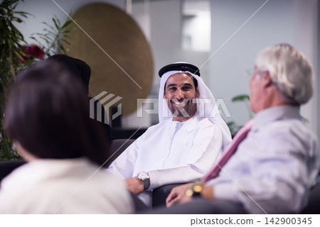 Middle Eastern business team meeting and networking in modern open office with smiling colleagues Middle Eastern business team meeting and networking in modern open office with smiling colleagues 142900345