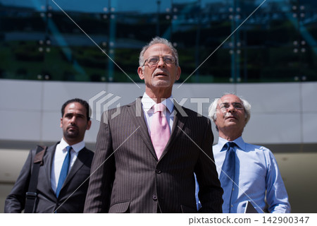 Middle Eastern business leaders standing confidently outside a modern corporate office after a meeting Middle Eastern business leaders standing confidently outside a modern corporate office after a meeting 142900347