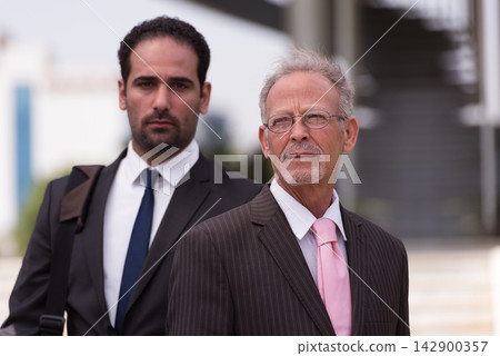 Middle Eastern business partners in suits at a modern corporate startup meeting outdoors Middle Eastern business partners in suits at a modern corporate startup meeting outdoors 142900357