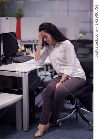 Middle Eastern businesswoman stressed at her desk in a modern open office during a busy workday Middle Eastern businesswoman stressed at her desk in a modern open office during a busy workday 142900359