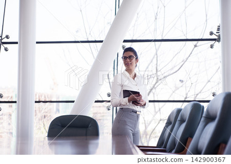 Middle Eastern businesswoman standing in modern open office during a corporate meeting and startup planning session Middle Eastern businesswoman standing in modern open office during a corporate meeting and startup planning session 142900367
