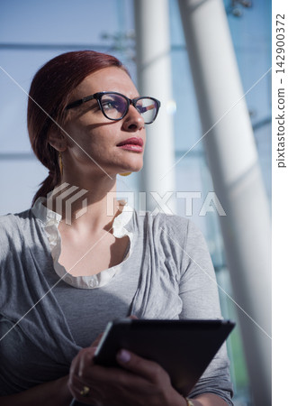 Middle Eastern businesswoman in modern office holding tablet and looking thoughtful during a startup meeting Middle Eastern businesswoman in modern office holding tablet and looking thoughtful during a startup meeting 142900372