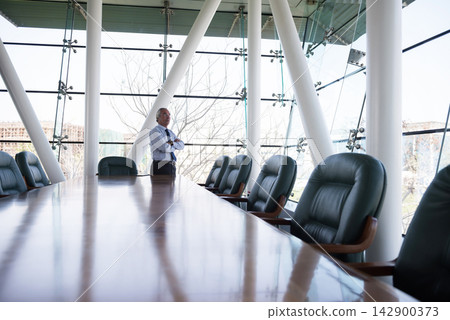 Middle Eastern executive standing confidently in a modern boardroom overlooking city views during a business meeting Middle Eastern executive standing confidently in a modern boardroom overlooking city views during a business meeting 142900373