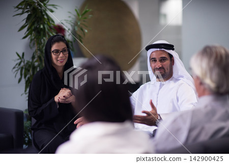Middle Eastern business team meeting and networking in modern open office with smiling colleagues Middle Eastern business team meeting and networking in modern open office with smiling colleagues 142900425