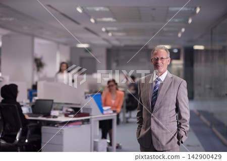 Experienced Arab businessman standing confidently in a modern open office with diverse startup team Experienced Arab businessman standing confidently in a modern open office with diverse startup team 142900429