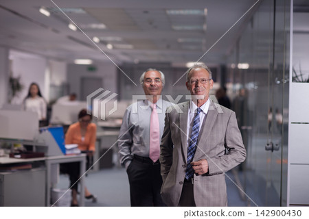 Senior business executives smiling in a modern open-plan office during a professional meeting 142900430