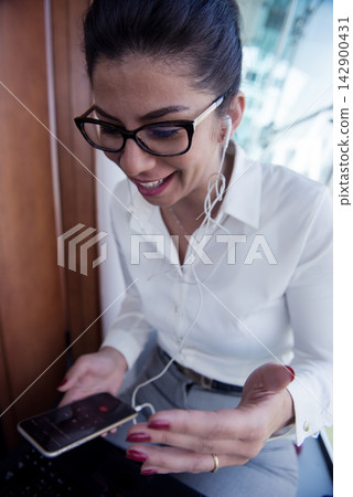 Professional woman in a modern office smiling during a mobile video call on business meeting Professional woman in a modern office smiling during a mobile video call on business meeting 142900431