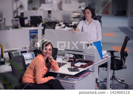 Business colleagues in modern open-plan office smiling and collaborating at their desks Business colleagues in modern open-plan office smiling and collaborating at their desks 142900528