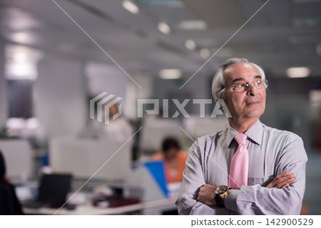 Confident senior executive in open office looking thoughtful during a corporate business meeting Confident senior executive in open office looking thoughtful during a corporate business meeting 142900529
