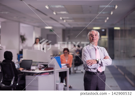 Middle Eastern senior manager standing confidently with arms crossed in modern open-plan office Middle Eastern senior manager standing confidently with arms crossed in modern open-plan office 142900532