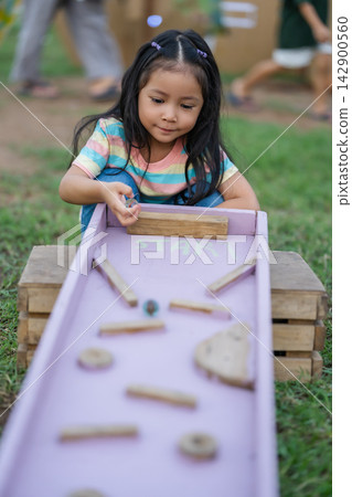 preschool child girl playing with wooden marble track game in park preschool child girl playing with wooden marble track game in park 142900560