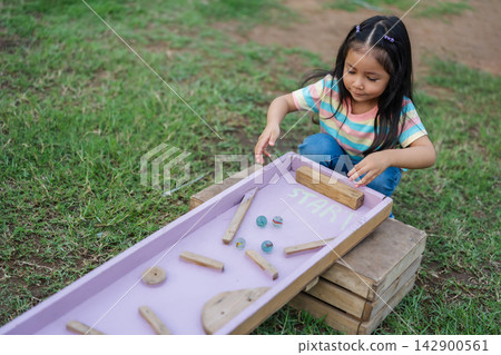 preschool child girl playing with wooden marble track game in park preschool child girl playing with wooden marble track game in park 142900561