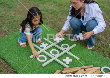 preschool child girl and mother playing tic tac toe game on green mat preschool child girl and mother playing tic tac toe game on green mat 142900562