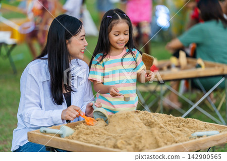 preschool child girl and mother playing with sand in sandbox outdoor preschool child girl and mother playing with sand in sandbox outdoor 142900565