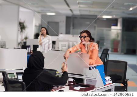 Business colleagues collaborating and smiling in a modern open-plan office with woman in hijab Business colleagues collaborating and smiling in a modern open-plan office with woman in hijab 142900681