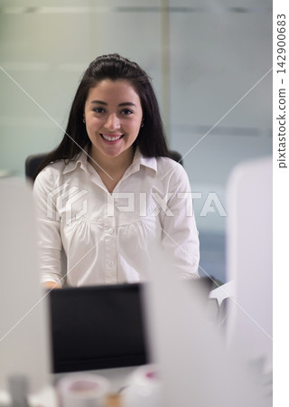 Smiling businesswoman working at a modern startup office desk during a professional meeting Smiling businesswoman working at a modern startup office desk during a professional meeting 142900683