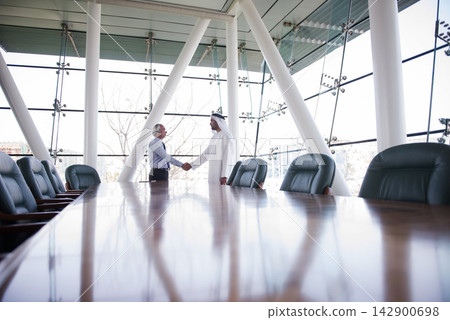Business meeting handshake between Middle Eastern and Western executives in a modern corporate boardroom Business meeting handshake between Middle Eastern and Western executives in a modern corporate boardroom 142900698
