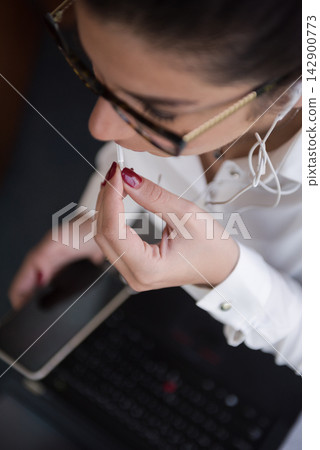 Middle Eastern business woman in modern office using earphones with smartphone and laptop during work Middle Eastern business woman in modern office using earphones with smartphone and laptop during work 142900773