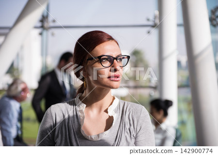 Thoughtful businesswoman in modern open-plan office lounge during a busy corporate meeting with colleagues Thoughtful businesswoman in modern open-plan office lounge during a busy corporate meeting with colleagues 142900774