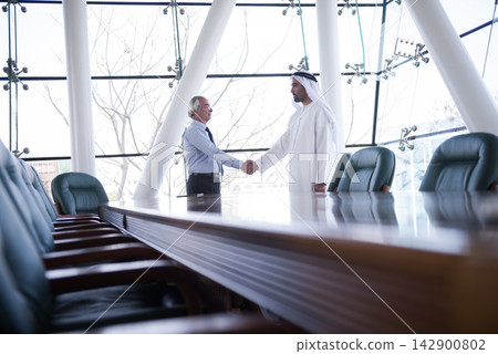 Middle Eastern and Western businessmen shaking hands in a modern corporate meeting room Middle Eastern and Western businessmen shaking hands in a modern corporate meeting room 142900802