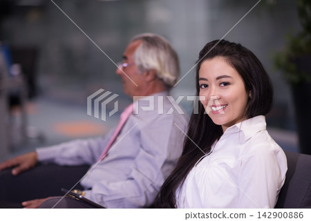 Smiling young professional woman in office during a business meeting with a senior colleague in a lobby Smiling young professional woman in office during a business meeting with a senior colleague in a lobby 142900886